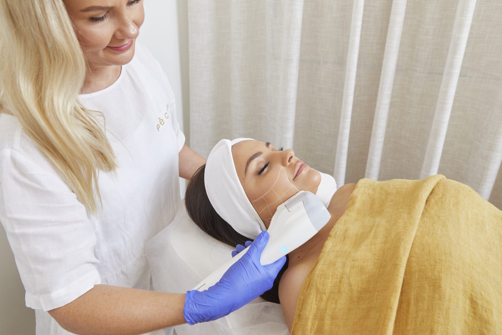 Pêche nurse performing Ultraformer III HIFU treatment on a client's jawline and neck